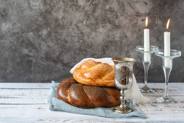 Shabbat Shalom - challah bread, shabbat wine and candles on grey background. With copy space.
